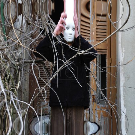 Téléchargez les photos : Femme avec masque sur le visage sur le vieux bâtiment - en image libre de droit