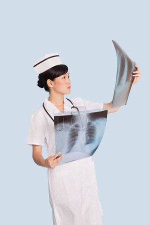 Photo for Female doctor analyzing x-ray reports over light blue background - Royalty Free Image