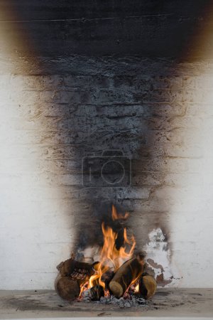 Photo for Burning wood against stained wall - Royalty Free Image