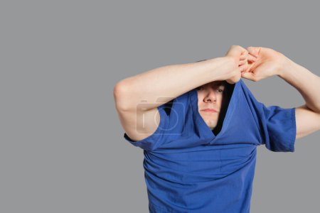 Photo for "Young man removing t-shirt over colored background" - Royalty Free Image