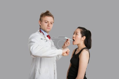 Photo for Doctor checking temperature of female patient - Royalty Free Image