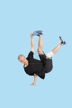 Téléchargez les photos : Briser danseur performant handstand sur fond bleu - en image libre de droit