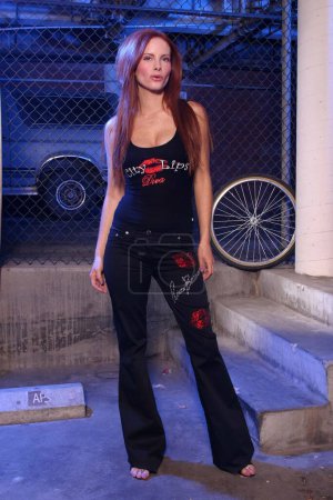 Photo for Beautiful actress Phoebe Price on photo shoot in basement with car and bicycle wheel. California, Santa Monica. - Royalty Free Image