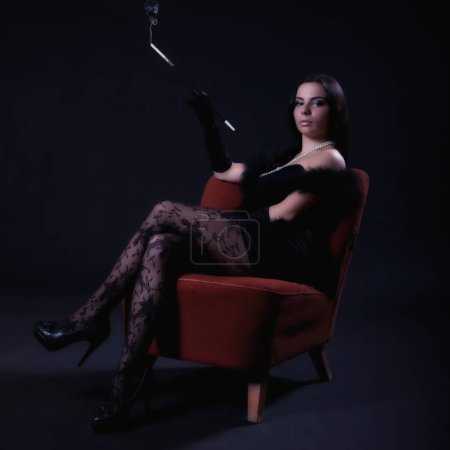 Foto de Mujer retro en silla roja con cigarro - Imagen libre de derechos