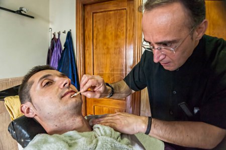 Téléchargez les photos : Barber treats small wounds after shaving with razor in a barber' - en image libre de droit