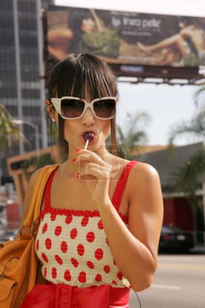 Photo for Bai Ling wearing polka dress. actress with lollipop candy In Front of Billboard in street, upcoming reality TV show "Stranded With A Star". Corner of Selma and Cahuenga. Hollywood, CA. 07-19-06 - Royalty Free Image