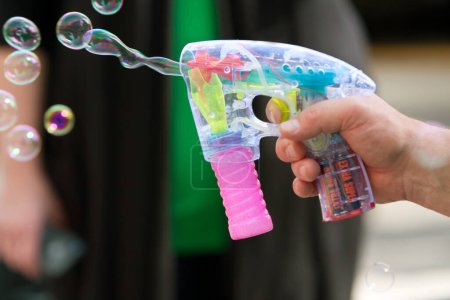 Foto de Mano del hombre utiliza pistola de burbujas para disparar burbujas en el aire - Imagen libre de derechos