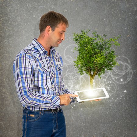Téléchargez les photos : Homme tenir comprimé pc avec arbre vert - en image libre de droit