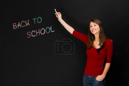 Photo for Back to school written on board with young teacher - Royalty Free Image