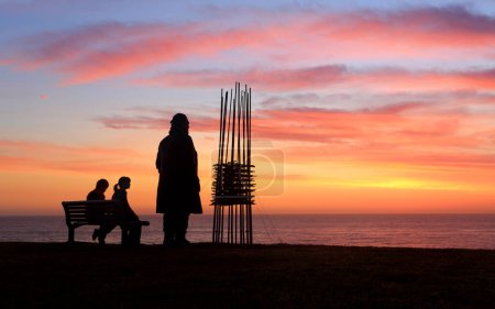 Téléchargez les photos : Deux sculptures deux spectateurs, lever de soleil Sculpture au bord de la mer - en image libre de droit
