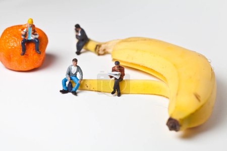 Photo for Miniature people in action sitting on a banana - Royalty Free Image