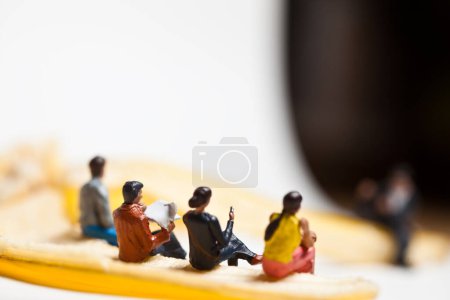 Téléchargez les photos : Des gens miniatures en action assis sur une banane - en image libre de droit