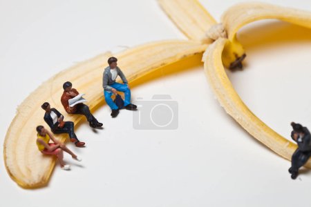 Téléchargez les photos : Des gens miniatures en action assis sur une banane - en image libre de droit