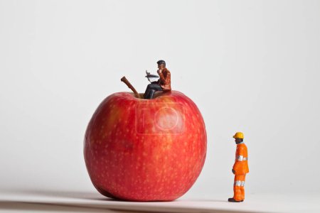 Photo for Miniature people in action sitting on an apple - Royalty Free Image