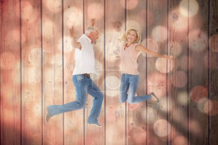 Foto de Imagen compuesta de la excitada pareja animando y saltando - Imagen libre de derechos