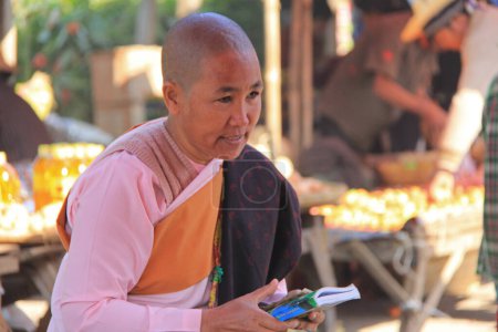 Foto de MANDALAY, MYANMAR- 24 DE NOVIEMBRE: Una monja budista camina por una calle de la ciudad el 24 de noviembre de 2015 en Mandalay, Myanmar - Imagen libre de derechos