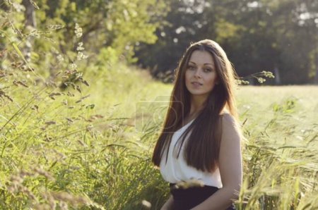 Foto de Young woman at green meadow. Daytime view - Imagen libre de derechos