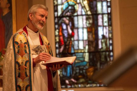Téléchargez les photos : A priest holding a bible in church - en image libre de droit