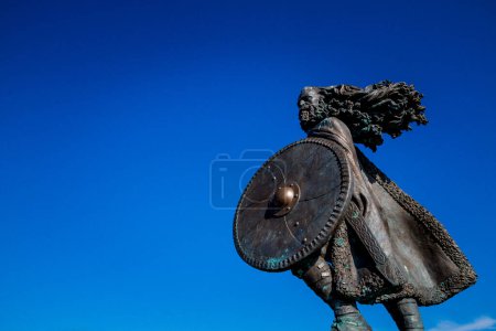 Photo for Bronze warrior sculpture with shield against blue sky - Royalty Free Image