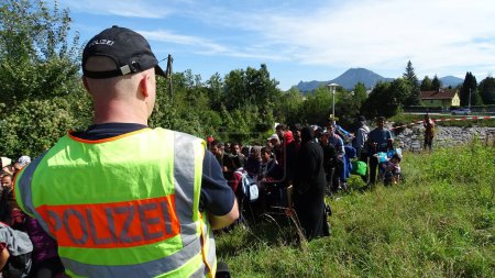 Photo for GERMANY, Freilassing: A German policeman watches over refugees at the gates of Freilassing, Bavaria, on the German side of the Germany-Austria border, September 16, 2015. - Royalty Free Image