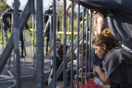 Foto de CROACIA, Hármica: Refugiados de pie y esperando en un puente en el pueblo de Hármica, Croacia, en la frontera de Eslovenia el 19 de septiembre de 2015, después de que el gobierno esloveno bloqueara la entrada de refugiados al país con la policía antidisturbios. - Imagen libre de derechos