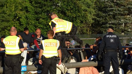 Téléchargez les photos : ALLEMAGNE, Freilassing : Des réfugiés arrêtés par la police alors qu'ils entrent en Allemagne depuis l'Autriche à la gare de Freilassing, le 21 septembre 2015. La station est devenue un immense camp de traitement pour les migrants se dirigeant vers l'Allemagne, à la suite des contrôles aux frontières - en image libre de droit