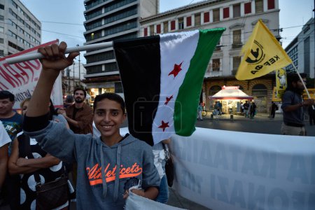 Téléchargez les photos : GRÈCE, Athènes : Un garçon agite un drapeau de l'opposition syrienne alors qu'il participe à une manifestation antifasciste à Athènes, le 25 septembre 2015. - en image libre de droit