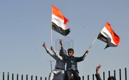 Foto de YEMEN, Sanaa: Niños sostienen banderas yemeníes durante una manifestación en Sanaa el 2 de octubre de 2015, contra las operaciones militares en curso llevadas a cabo por la coalición liderada por Arabia Saudita. - Imagen libre de derechos