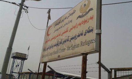 Téléchargez les photos : IRAQ, Kurdistan : Extérieurs d'un bâtiment et d'une camionnette au camp de réfugiés de Kawergosk, au Kurdistan, le 4 octobre 2015.Certains cas de choléra sont apparus à Bagdad et dans le sud de l'Irak, ce qui a amené des organisations humanitaires dans le camp pour fournir des informations. - en image libre de droit