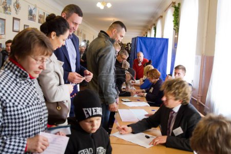 Foto de UCRANIA, Kiev: El alcalde de Kiev, Vitaly Klitschko, su esposa Natalia, y su hermano Vladimir Klitschko se preparan para emitir sus votos en un centro de votación en Kiev el 25 de octubre de 2015. - Imagen libre de derechos