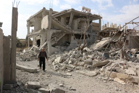 Téléchargez les photos : SYRIE, Damas : Un Syrien marche au milieu de bâtiments endommagés dans le quartier de Marj al-Sultan à l'est de Damas le 24 octobre 2015. - en image libre de droit