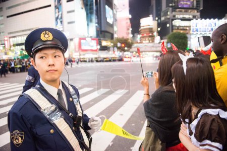 Téléchargez les photos : JAPON, Tokyo : Un policier s'occupe de la foule alors que les gens participent à un défilé d'Halloween à Tokyo le 31 octobre 2015. Des dizaines de milliers de personnes se sont rassemblées dans le quartier de la mode Shibuya de Tokyo pour célébrer Halloween. - en image libre de droit