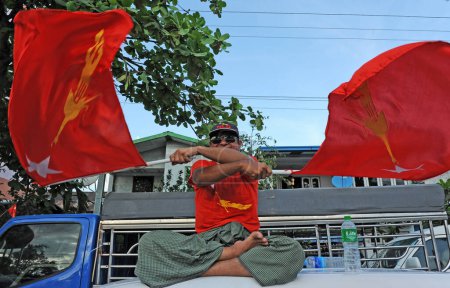 Téléchargez les photos : MYANMAR, Yangon : Un homme secoue deux drapeaux du Myanmar tandis que des dizaines de milliers de personnes se rassemblent à Yangon le 1er novembre 2015 - en image libre de droit