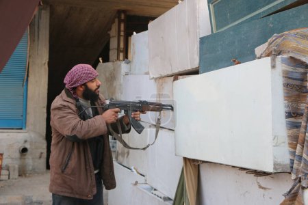 Téléchargez les photos : SYRIE, Harasta : Un rebelle contrôle la présence ennemie à travers une barricade artisanale tandis que les affrontements entre plusieurs factions rebelles, l'armée syrienne et ses alliés s'intensifient à Harasta, dans la banlieue nord de la capitale syrienne Damas, le 2 novembre 2015 - en image libre de droit