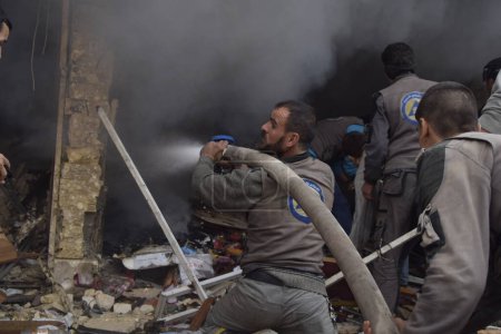 Téléchargez les photos : SYRIE, Irbin : Les pompiers tentent de prendre le contrôle des tirs après que des avions de guerre aient visé l'une des rues principales du village d'Irbin, à l'est de Damas, le 7 novembre 2015 - en image libre de droit