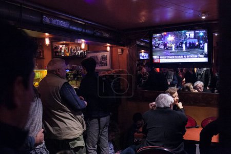 Photo for FRANCE, Paris: Parisians in a bar watch television coverage of a string of shootings and explosions that took place in the capital on November 13, 2015. - Royalty Free Image