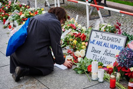 Foto de GERMANY, Berlin: A woman leaves a candle on the floor in front of the French embassy in Berlin, on November 14, 2015, to pay tribute to the Paris November-13 terror attacks's victims. - Imagen libre de derechos