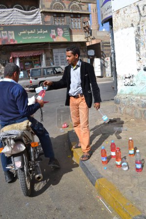 Téléchargez les photos : YEMEN, Sanaa : Un négociant du marché noir vend des bouteilles d'essence à Sanaa, la capitale du Yémen, le 7 novembre 2015, alors que les stations-service ont fermé depuis le début de la guerre et les bombardements saoudiens sur le pays - en image libre de droit