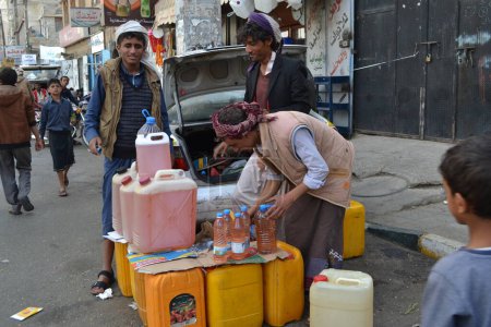 Téléchargez les photos : YEMEN, Sanaa : Un négociant du marché noir vend des bouteilles d'essence à Sanaa, la capitale du Yémen, le 7 novembre 2015, alors que les stations-service ont fermé depuis le début de la guerre et les bombardements saoudiens sur le pays - en image libre de droit