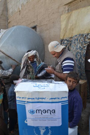 Foto de YEMEN, Sanaa: Miembros de la organización humanitaria local Mona Relief distribuyen ropa a familias desplazadas y personas pobres cerca de Sanaa, la capital de Yemen, el 11 de noviembre de 2015. - Imagen libre de derechos