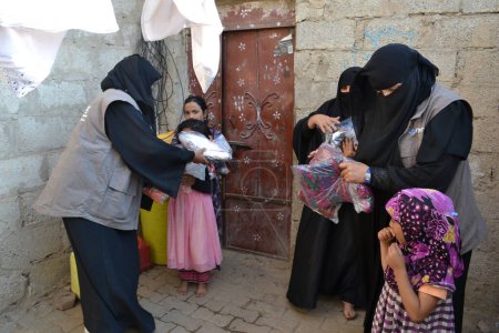 Téléchargez les photos : YEMEN, Sanaa : Des membres de l'organisation humanitaire locale Mona Relief distribuent des vêtements aux familles déplacées et aux personnes pauvres près de Sanaa, la capitale du Yémen, le 11 novembre 2015. - en image libre de droit