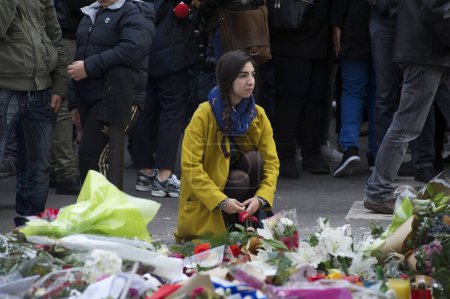 Téléchargez les photos : FRANCE, Paris : Des gens se sont rassemblés rue Bichat, près de l'une des scènes de crime des attentats de Paris, pour participer à une minute de silence pour les victimes des attentats, le 16 novembre 2015. - en image libre de droit