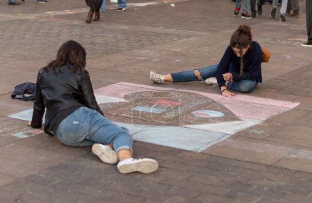 Téléchargez les photos : FRANCE, Toulouse : Deux filles dessinent sur le sol avec des bâtons de craie pour rendre hommage aux victimes des attentats de Paris du 13 novembre 2015, place du Capitole, à Toulouse, dans le sud de la France, le 17 novembre 2015. - en image libre de droit