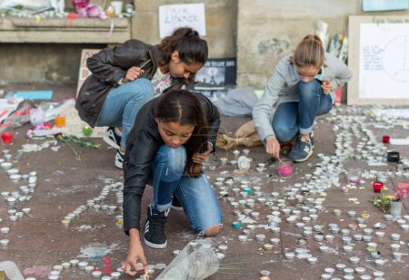 Téléchargez les photos : FRANCE, Toulouse : Des filles allument des bougies pour rendre hommage aux victimes des attentats du 13 novembre 2015 à Paris, place du Capitole, à Toulouse, Sud de la France, le 17 novembre 2015. - en image libre de droit