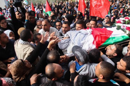 Foto de BANCO DEL ESTE, Ramallah: Oficiales de seguridad palestinos llevan el cuerpo de Ibrahim Dawood, de 16 años, durante su funeral en la ciudad de Ramallah, Cisjordania, el 26 de noviembre de 2015. - Imagen libre de derechos