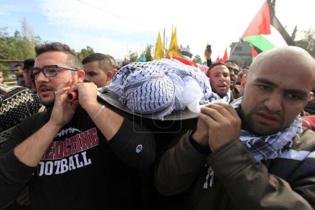 Foto de BANCO DEL ESTE, Ramallah: Oficiales de seguridad palestinos llevan el cuerpo de Ibrahim Dawood, de 16 años, durante su funeral en la ciudad de Ramallah, Cisjordania, el 26 de noviembre de 2015. - Imagen libre de derechos