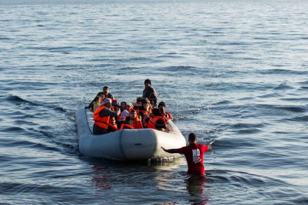 Foto de GRECIA, Lesbos: refugiados y migrantes llegan en un barco abarrotado a una playa en la isla griega de Lesbos el 6 de diciembre de 2015. Muchos de los barcos y balsas continúan haciendo el viaje de Turquía a Grecia cada día. - Imagen libre de derechos