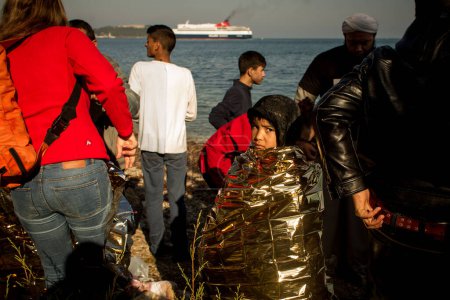 Foto de GRECIA, Lesbos: refugiados y migrantes llegan en un barco abarrotado a una playa en la isla griega de Lesbos el 6 de diciembre de 2015. Muchos de los barcos y balsas continúan haciendo el viaje de Turquía a Grecia cada día. - Imagen libre de derechos