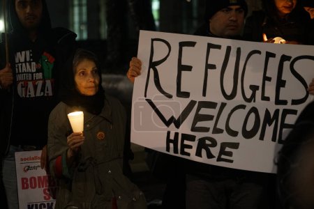 Téléchargez les photos : ANGLETERRE, Londres : Des personnes en soutien aux réfugiés se sont rassemblées à Londres le 12 décembre 2015 pour organiser une veillée de Noël devant Downing Street.Les manifestants ont tenu des bougies et des pancartes appelant à l'accueil des réfugiés. - en image libre de droit