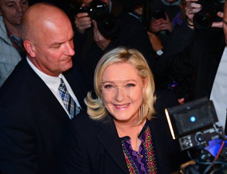 Téléchargez les photos : FRANCE, Hnin-Beaumont : Marine Le Pen (C), leader du Front national d'extrême droite (FN), part après avoir prononcé un discours à la suite de l'annonce des résultats du deuxième tour des élections régionales françaises à Henin-Beaumont le 13 décembre 2015. - en image libre de droit